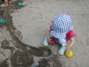 女の子が砂場で座って遊んでいる