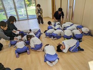 園児が屋内で避難姿勢をとる様子の写真