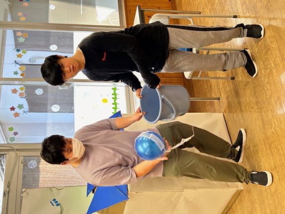 職員と一緒に手作りけん玉で遊んでいる様子