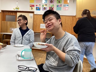 職員と児童が並んでホットケーキを食べる写真