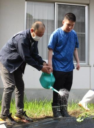 植えた苗に水をあげる児童の写真