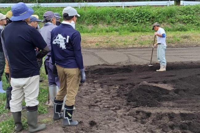 訓練指導員が鍬の扱い方を説明しています。