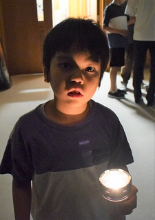 懐中電灯で自分を照らす児童
