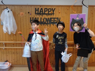 ハロウィンの文字の前でポーズをとる子どもと職員