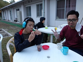 柿を頬張る児童とピースをする職員