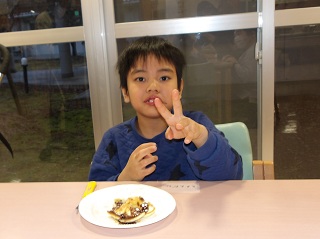 ホットケーキを前にピースをする児童