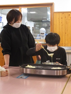 ホットプレートに生地を広げる児童
