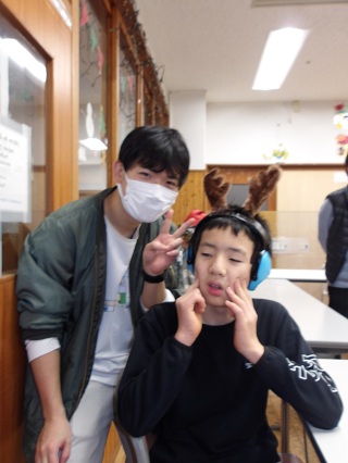 ピースサインをする児童と職員