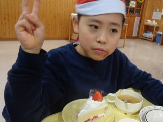 ケーキを前にピースする児童