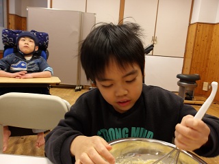 泡立て器で生地を混ぜる児童