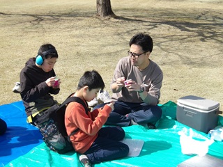 レジャーシートの上でおやつを食べる児童と職員