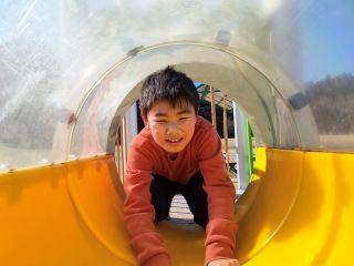 トンネル遊具をくぐる児童