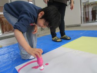 ピンクの絵の具で線を描く児童