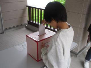 投票用紙を投票箱に入れている写真