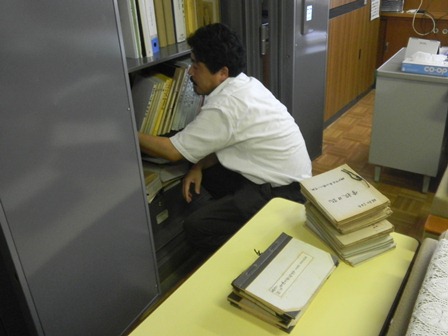 校長室に保管される綴類を調査する現代部会の石田委員の様子の写真