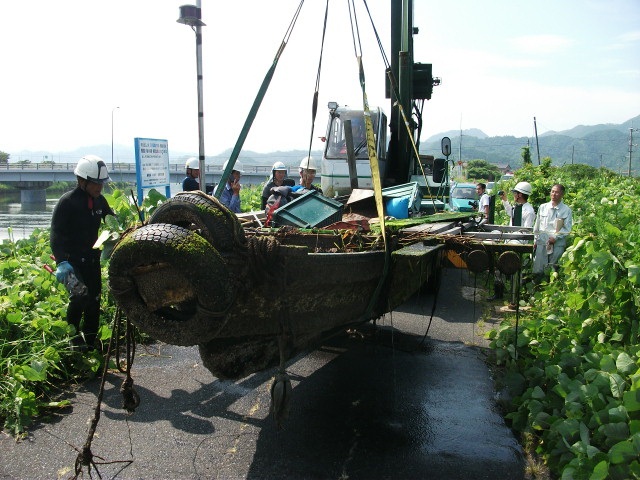 クレーン車で不法投棄されている車を移動する様子